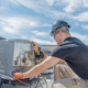 Side view of an HVAC technician at work fixing a unit