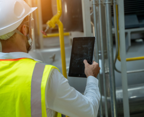 Portrait of electrician engineer use tablet computer taking notes at control room in factory.