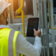 Portrait of electrician engineer use tablet computer taking notes at control room in factory.