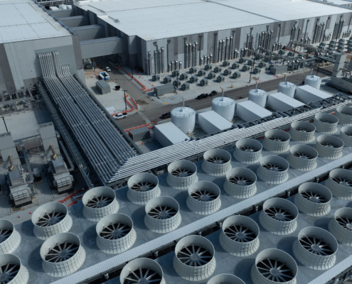 Aerial close-up of an AI data center showing large-scale cooling fans, pipelines, and industrial infrastructure